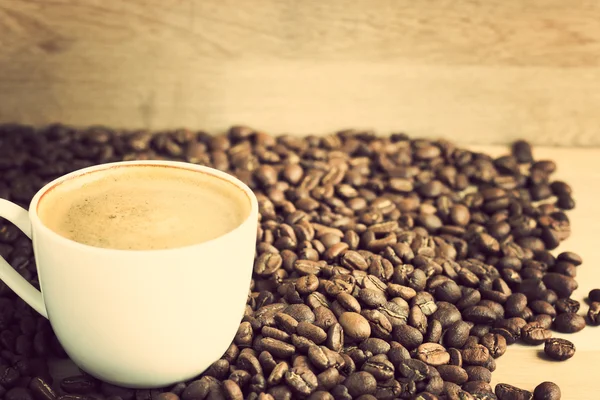 Kaffeetasse und Bohnen über Holz — Stockfoto