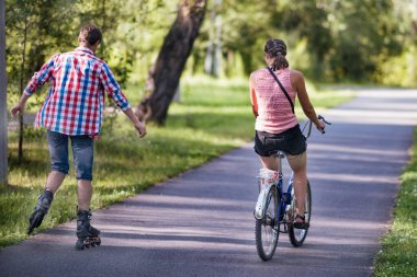 Yazın bisiklet süren ve parkta paten kayan iki arkadaş.. 