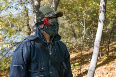 COVID-19 döneminde ormanda solunum maskesi ve koruyucu gözlük takan bir adam..