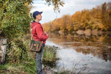 Yazın ormanda yürüyen akıllı telefonlu bir adam..