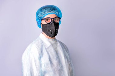 Mavi arka planda tıbbi solunum cihazı ve üniforma giyen bir doktor var. COVID-19 koruması.