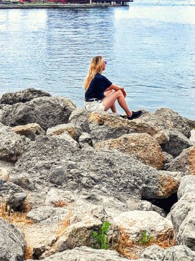 Deniz kıyısında oturmuş denize bakan bir kadın..