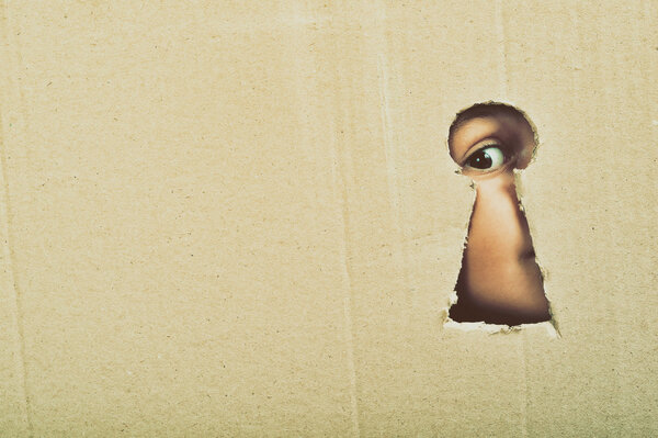 Глаз, смотрящий через замочную скважину на доске
