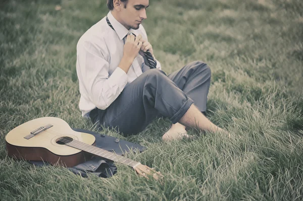 Niño sentado en la hierba con una guitarra — Foto de Stock