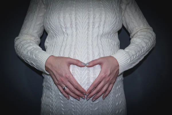 Donna incinta mostrando le mani in forma cuore — Foto Stock