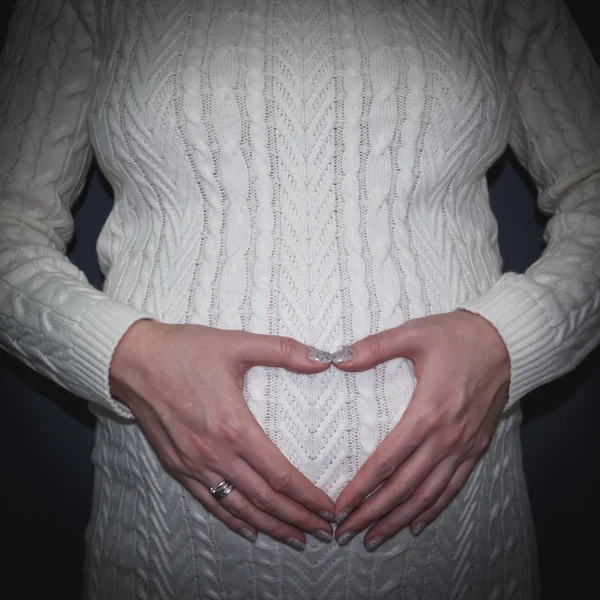 Беременная женщина показывает руки в форме сердца — стоковое фото
