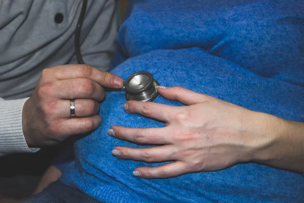 임신한 여자와 남자의 손에 청진 기의 배 — 스톡 사진