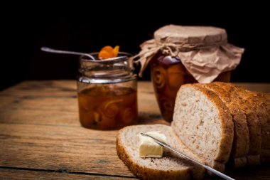 Ahşap masa üzerinde ekmek üzerine ev yapımı narenciye portakal reçeli