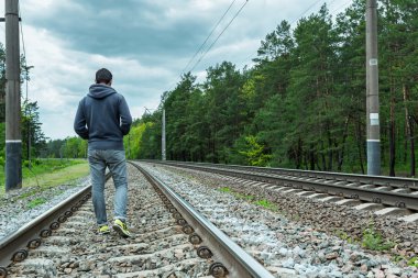 rayların üzerinde yürüyen adam