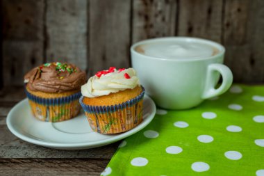 Kekler ahşap bir masa üzerinde sıcak cuppuccino