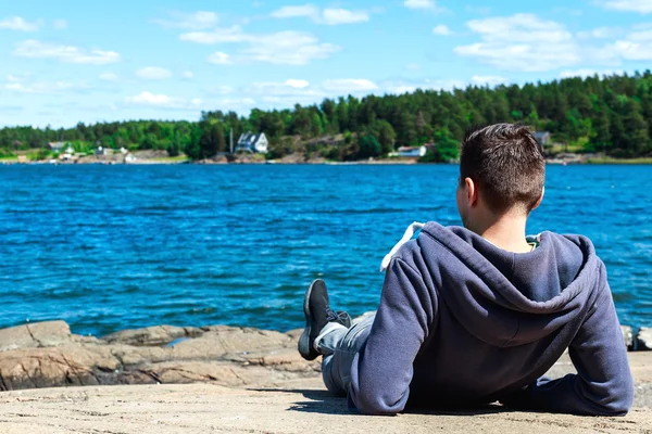 Stående bakifrån ung man sitter ute på havet — Stockfoto