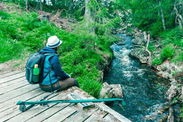 Junge Frau sitzt auf einer Holzbrücke am Teich beim Angeln — Stockfoto