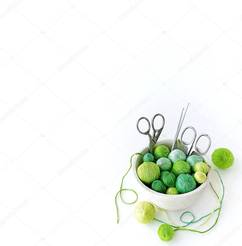 White basket with green knitting yarn.