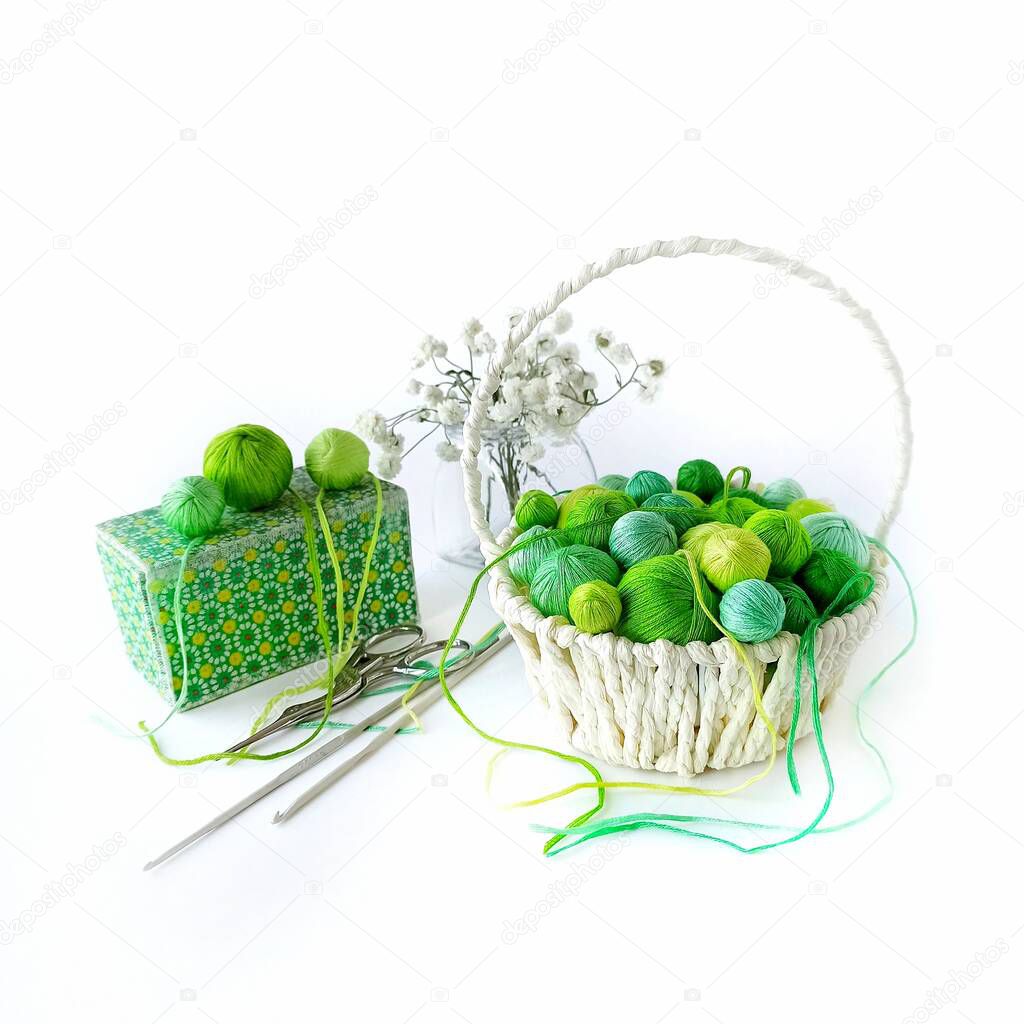 White basket with green knitting yarn and crochet hooks. 