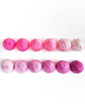 Beyaz arka planda izole edilmiş mor ve pembe iplik topları.