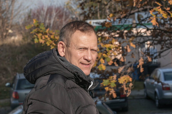 портрет мужчины средних лет на фоне городского осеннего пейзажа