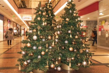 Alışveriş merkezinde top ve oyuncaklarla süslenmiş iki Noel ağacı.