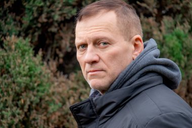 60 yaşında orta yaşlı bir adam sonbaharda doğanın arka planına karşı duruyor.