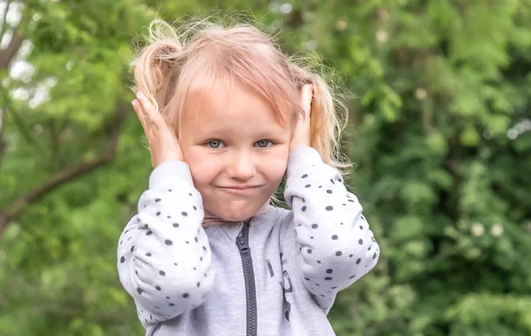 5歳のブロンドの女の子は不満な表情で耳を手で覆い — ストック写真