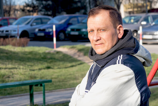 портрет мужчины среднего возраста 50-60 лет спортивного телосложения в пиджаке на фоне парковки