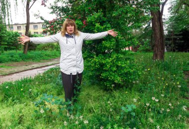 mature woman, middle-aged, pretty with blond hair, positive, cheerful, outdoors, resting, stretched out her arms in surprise