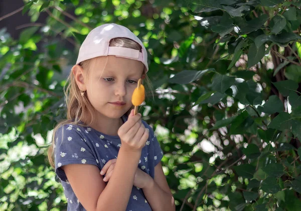 金髪の女の子は手に持っているアイスクリームを見ています6歳の子供の肖像画でポプシクル付きです — ストック写真