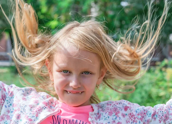 一个孩子的画像 一个快乐的漂亮女孩 一头蓬乱的金发 乳牙下垂 在公园的阳光下 — 图库照片