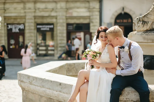 Bruden och brudgummen poserar vid fontänen — Stockfoto