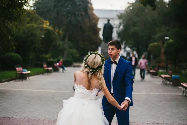 Novio sostiene novia en sus brazos y retorcido — Foto de Stock