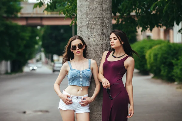 Dos hermosas chicas jóvenes posando en la ciudad — Foto de Stock