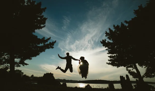 Sposo e sposa saltando contro il bel cielo — Foto Stock