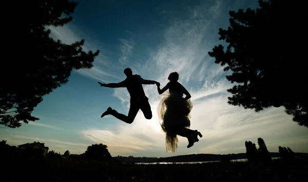 Groom and bride jumping against the beautiful sky — Stock Photo, Image