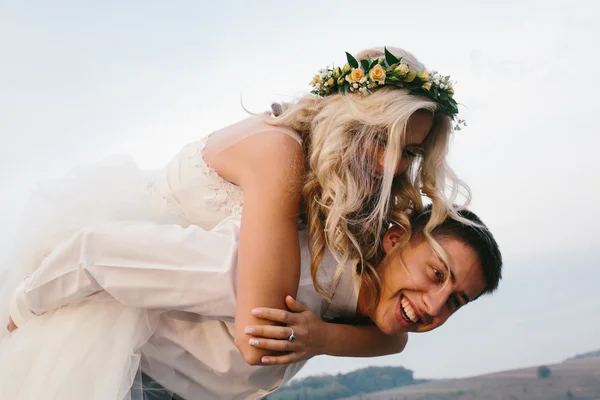 Noivo carrega noiva nas costas — Fotografia de Stock