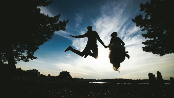 Brudgummen och bruden hoppa mot den vackra himlen — Stockfoto