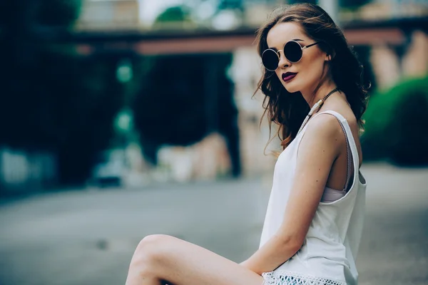 Beautiful girl in sunglasses sitting — Stock Photo, Image