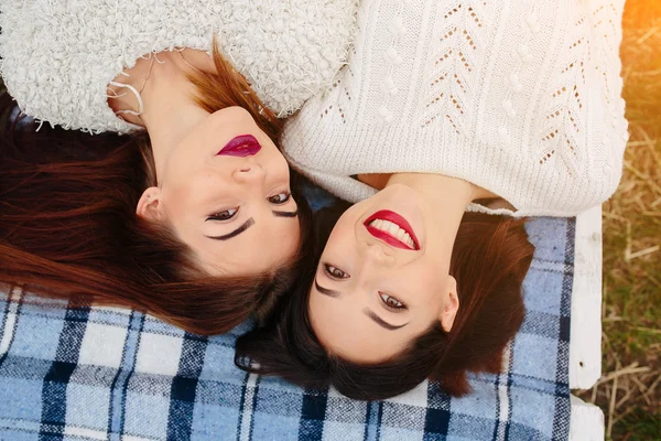 Dwie piękne dziewczyny leżą na ławce — Zdjęcie stockowe