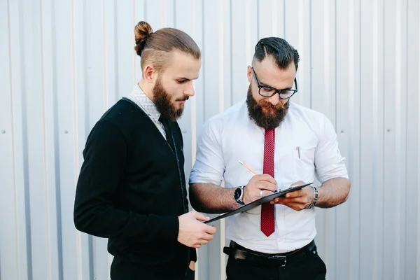 Два бородатых бизнесмена подписывают документы — стоковое фото