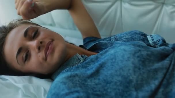 Vacker ung flicka poserar på en vit säng — Stockvideo