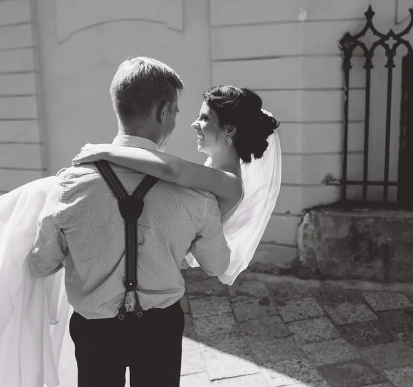 Groom carries bride in his arms — Stock Photo, Image