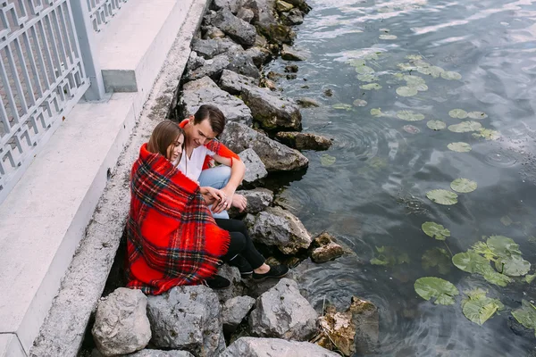 Unga vackra paret sitter på stranden — Stockfoto