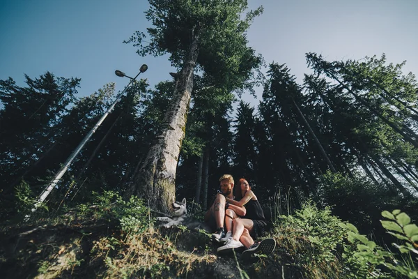 Belo casal sentado em uma floresta perto da árvore — Fotografia de Stock