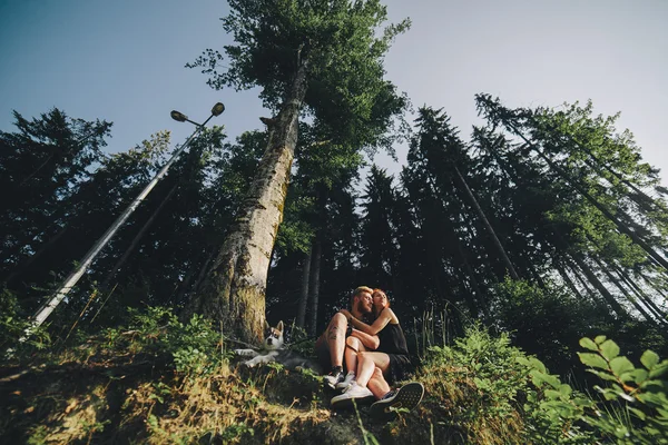 Красивая пара сидит в лесу рядом с деревом — стоковое фото