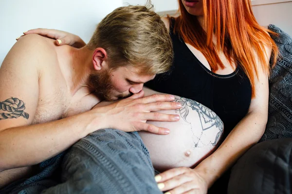 Femme enceinte et homme couché sur un lit — Photo