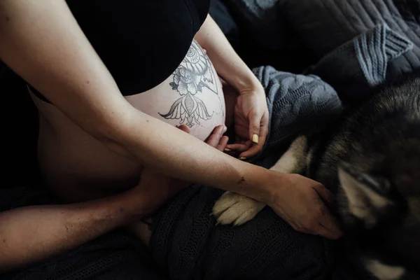 Femme enceinte, homme et chien assis sur un lit — Photo