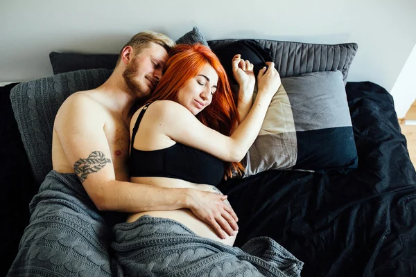 Беременная женщина и мужчина лежат на кровати — стоковое фото