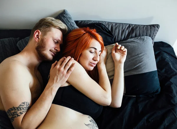 Těhotná žena a muž ležící na posteli — Stock fotografie