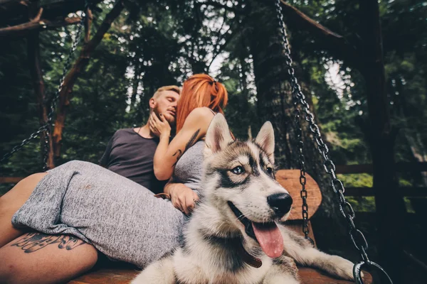Piękna para wraz z psem na huśtawce — Zdjęcie stockowe