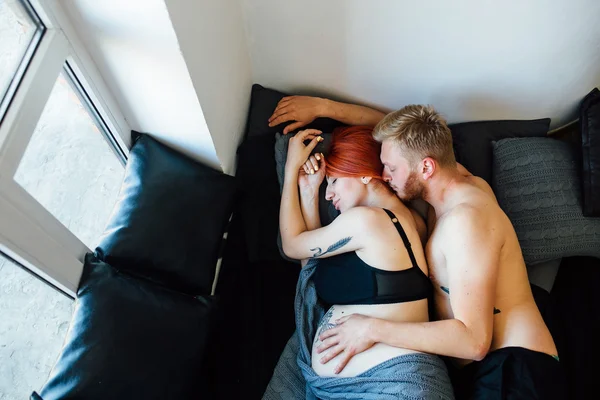 Zwangere vrouw en man liggend op een bed — Stockfoto
