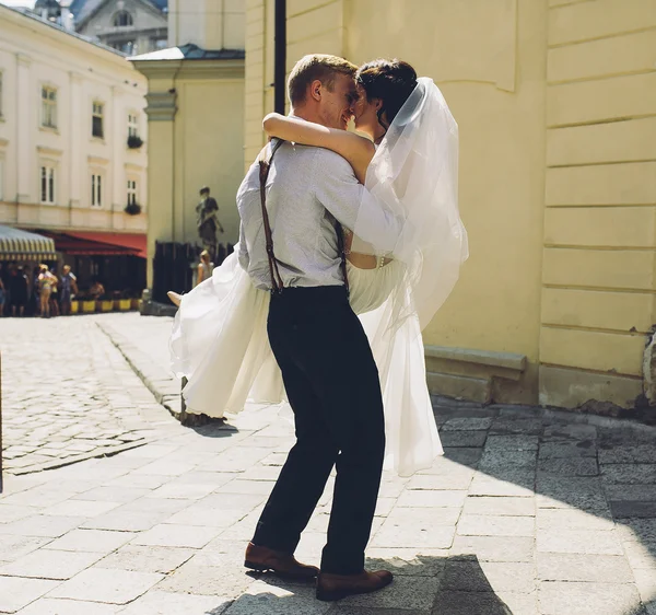 Noivo carrega noiva em seus braços — Fotografia de Stock