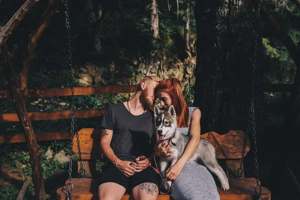 Красивая пара вместе с собакой на качелях — стоковое фото